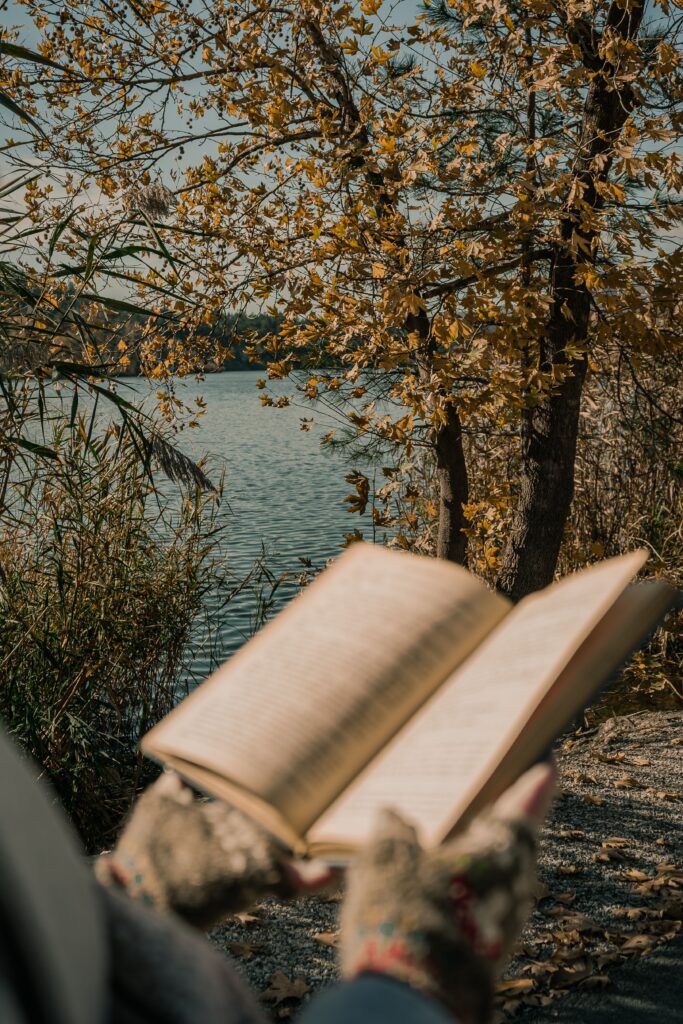 Enjoying a peaceful read by a lake with autumn leaves in Ankara, Türkiye.