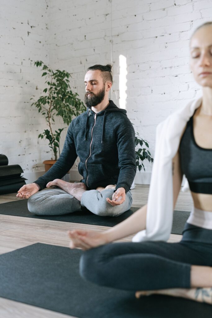 Serene indoor yoga practice with a man and woman in meditation pose.